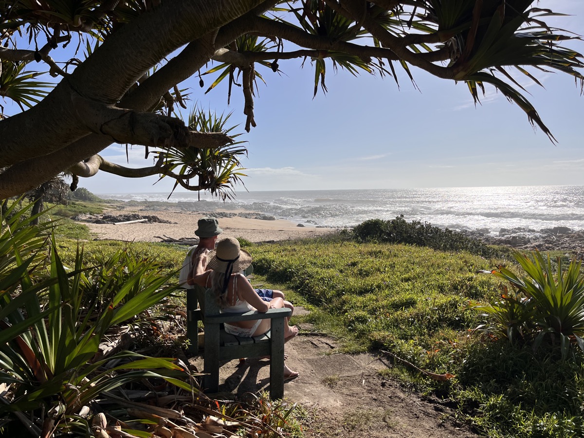 Couple assis sur un banc sous un arbre côtier face à l'océan Indien chaud, KwaZulu-Natal