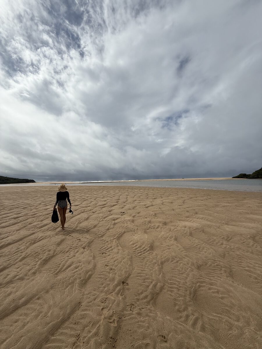 Une femme marchant seule sur la grande plage déserte de Kosi Bay sous un ciel dramatiquement nuageux