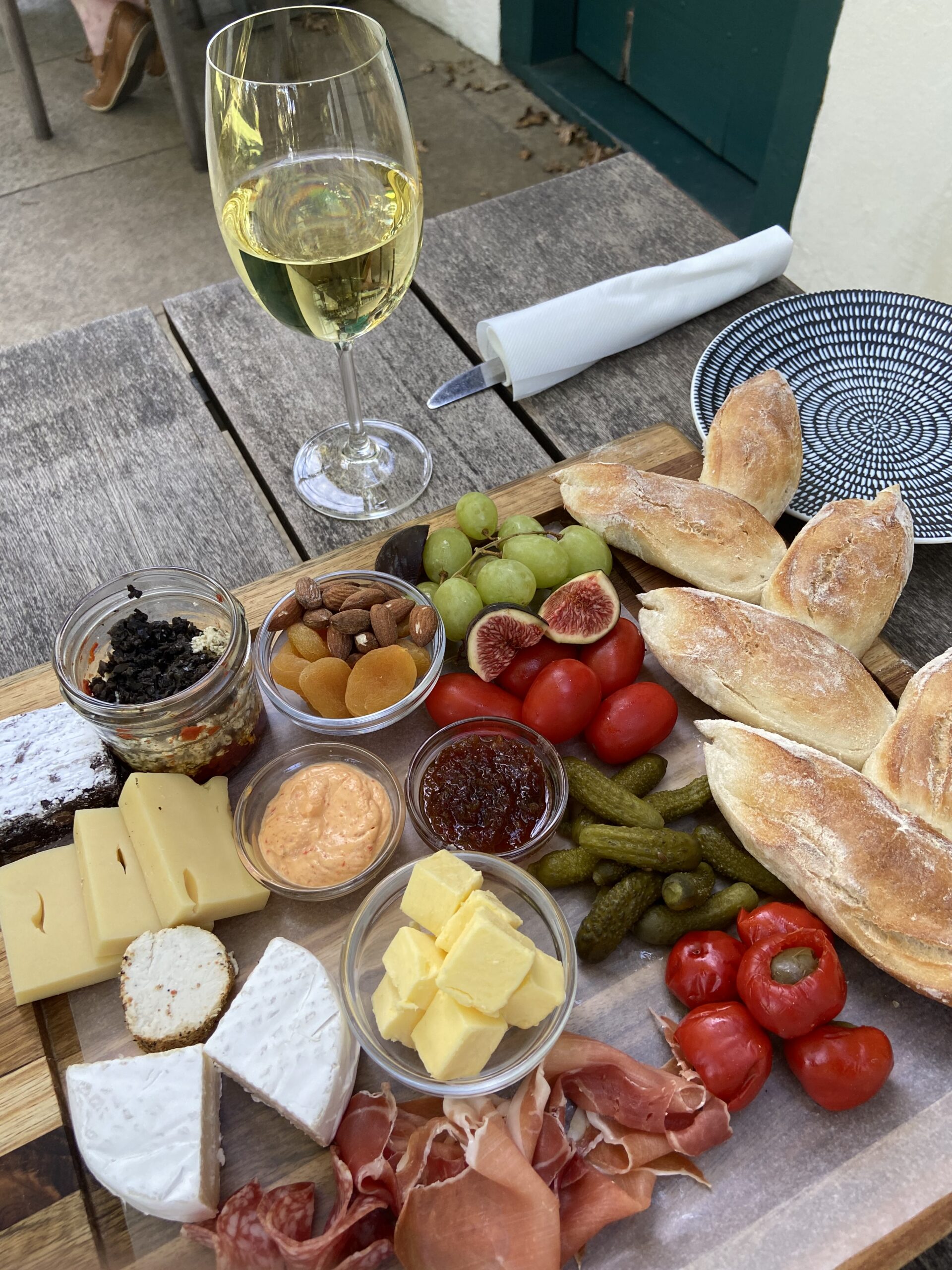 Un plateau de fromages, charcuterie et pain avec un verre de vin blanc dans un domaine viticole du Cap