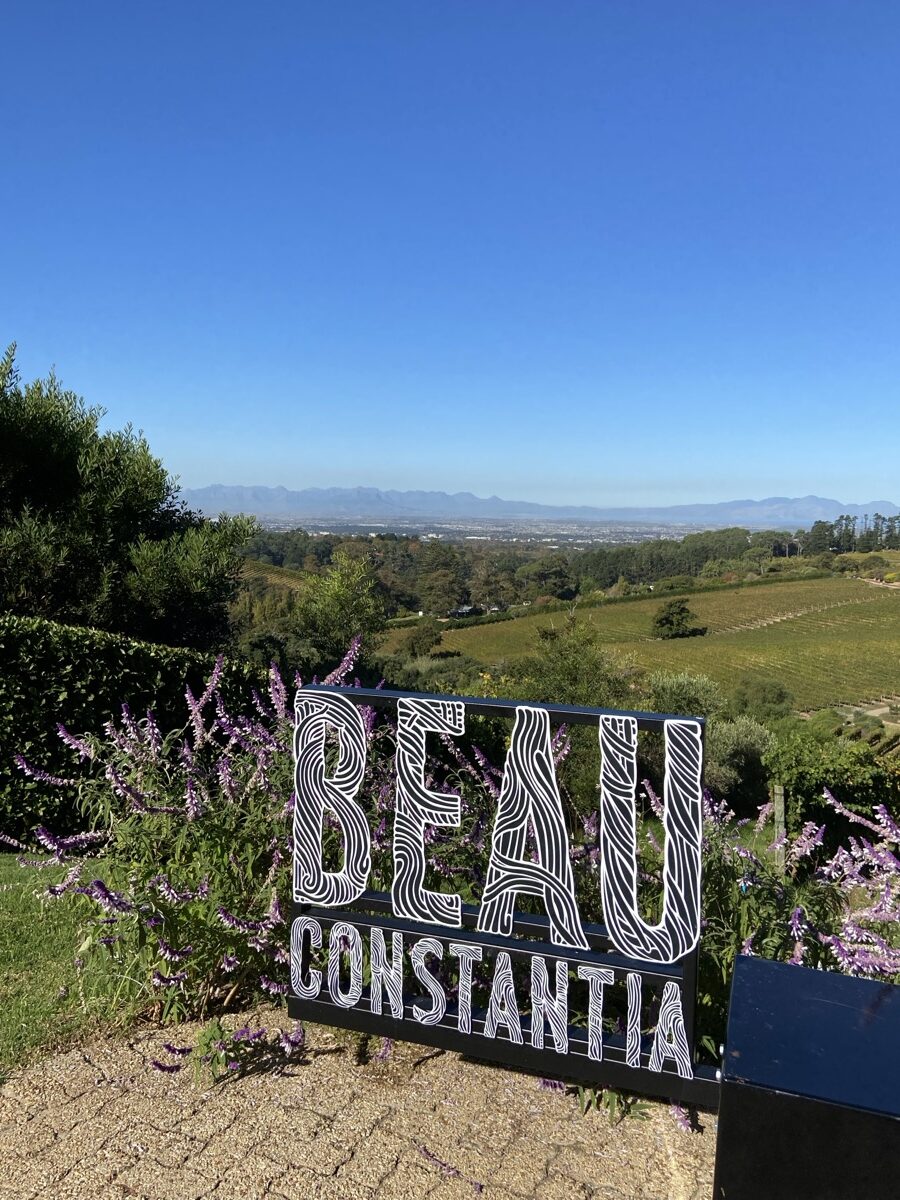 L'enseigne de Beau Constantia sur le flanc de la colline avec les vignobles et les montagnes du Cap qui s'étendent derrière